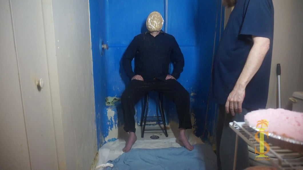 Man sitting on stool has pie pushed into face. Crust is cracking revealing the cream inside the pie