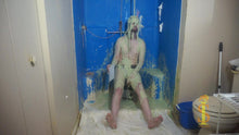 One man sitting on a low stool. His soles are visible. He's looking forward as green slime falls on his head