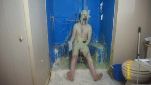 One man sitting on a low stool. His soles are visible. He's looking forward as green slime falls on his head