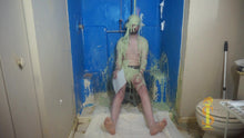One man sitting on a low stool. His soles are visible. He's looking forward as green slime falls on his head