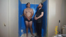 Two men standing in a bathroom with blue stalls.