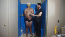 Two men in a bathroom with one with a pie in the face
