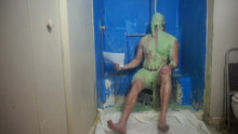 Man sitting on stool has green slime falling on him