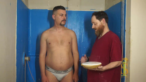 Man with goatee stands next to a man with a beard. The man with the beard holds a marshmallow cream pie