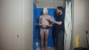 Man stands holding two pies, while a third pie has been pushed into his face